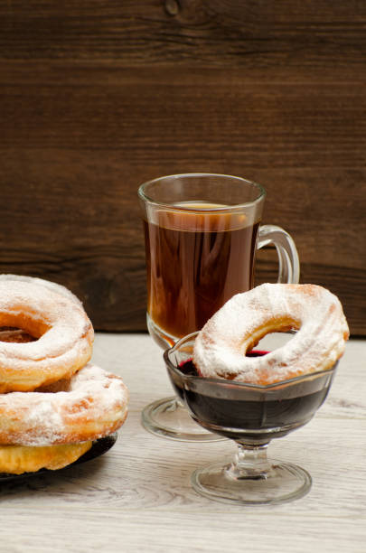 istock Donuts with icing sugar, a mug of tea and currant jam on a wooden background 648251806