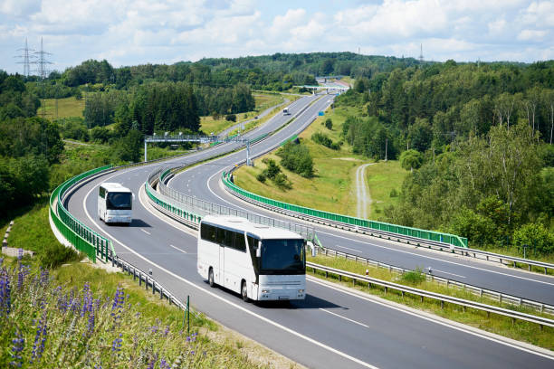 istock White buses driving on the highway winding through forested areas 648271254