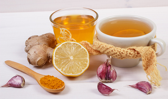 Cup of hot tea with lemon and ingredients for preparation warming beverage for flu and cold, health care concept