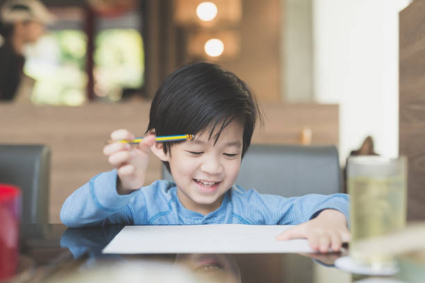 istock Asian child writing on white paper 648311220