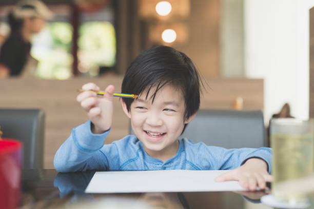 istock Asian child writing on white paper 648311224