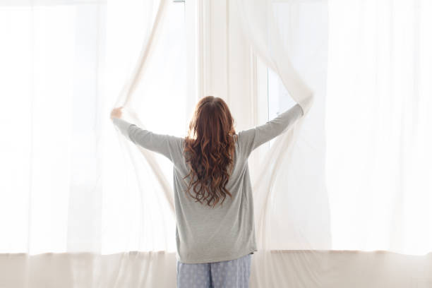 istock Female opens the curtains in the morning 648314830