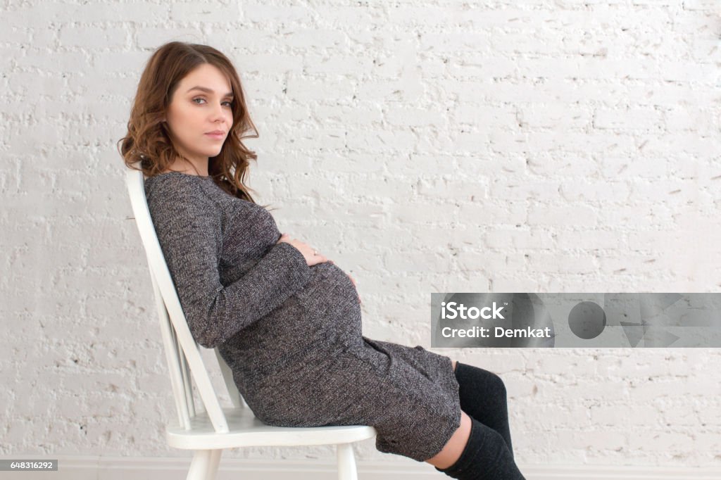 Sentado na cadeira posando de mulher grávida - Foto de stock de Cabelo Castanho royalty-free