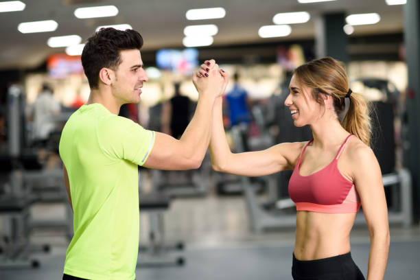 istock Smiling young man and woman doing high five in gym 648319232