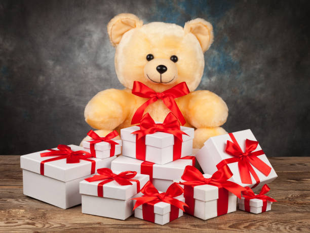 istock Teddy bear and white boxes with gifts on the old board 648319738