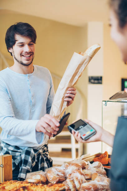 istock Young man paying with smart phone in the bakery 648323656