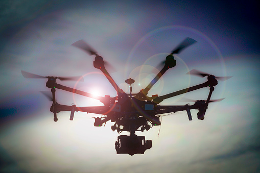 A silhouette of a flying drone take with the sun behind and a DSLR as a payload.