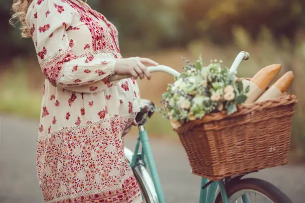 Photo of Pregnant belly against nature close-up. Woman retro French style with bicycle on a forest road