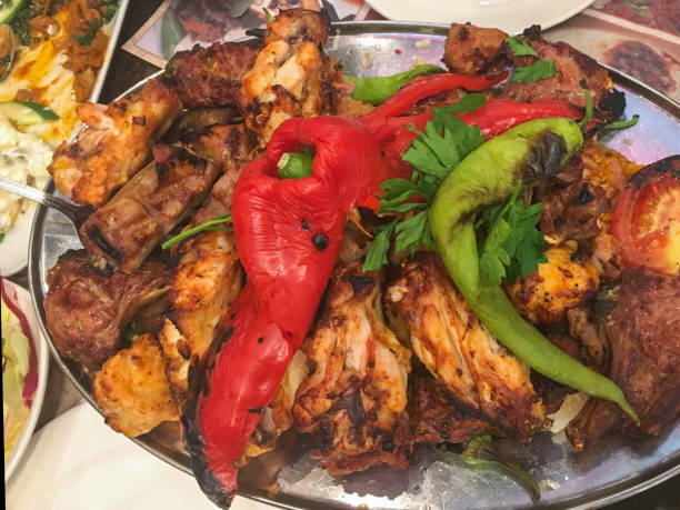 Close up mix grilled of variation meats, on a Turkish dinner meal. There's chicken, lamb grilled and paprika. The meats place on a stainless steel plate.