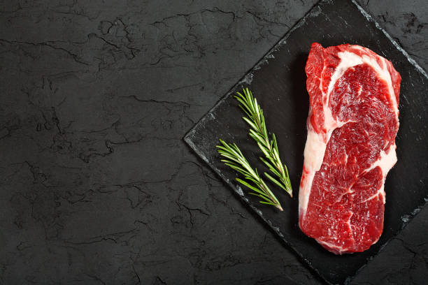 istock raw beef steak with rosemary and peppers on dark stone 648340662