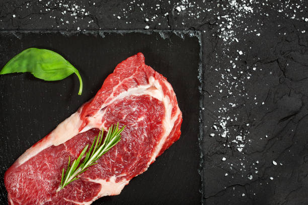 istock raw beef steak with rosemary and peppers on dark stone 648340674
