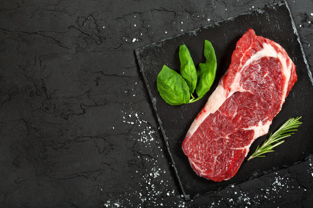 istock raw beef steak with rosemary and peppers on dark stone 648340680