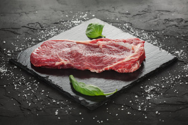 istock raw beef steak with rosemary and peppers on dark stone 648340690