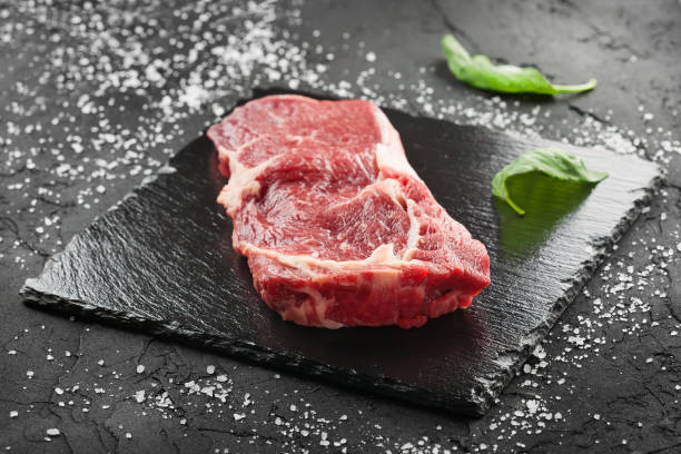 istock raw beef steak with rosemary and peppers on dark stone 648340692