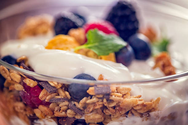 Eating healthy yogurt with cereals and fresh berries like raspberries, blueberries and blackberries