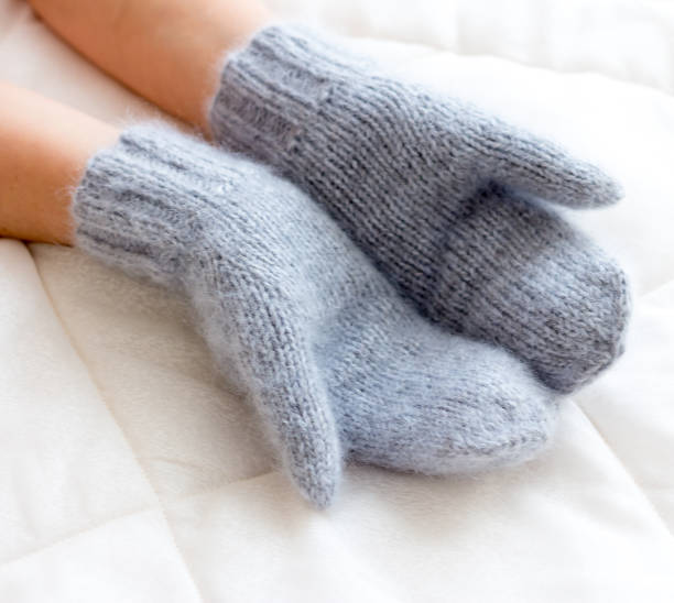 istock Gray blue mittens connected by hand from wool on a woman's arm 648359130