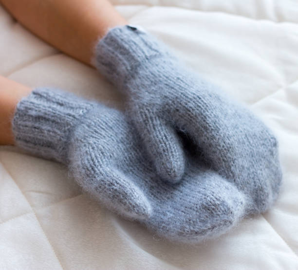 istock Gray blue mittens connected by hand from wool on a woman's arm 648359228