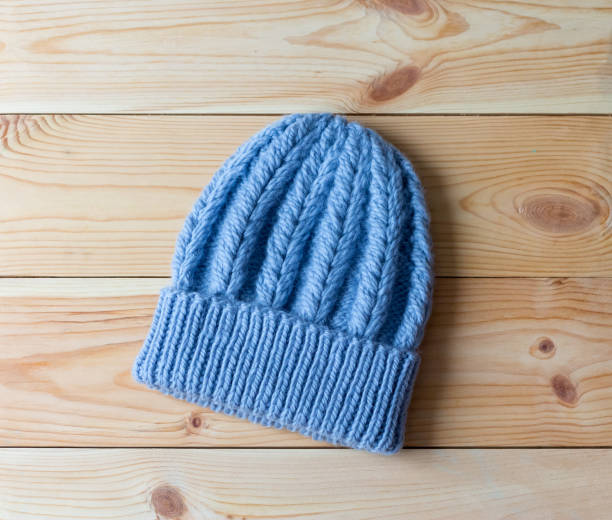istock Blue hat knitted by hand from wool on wooden background 648359472