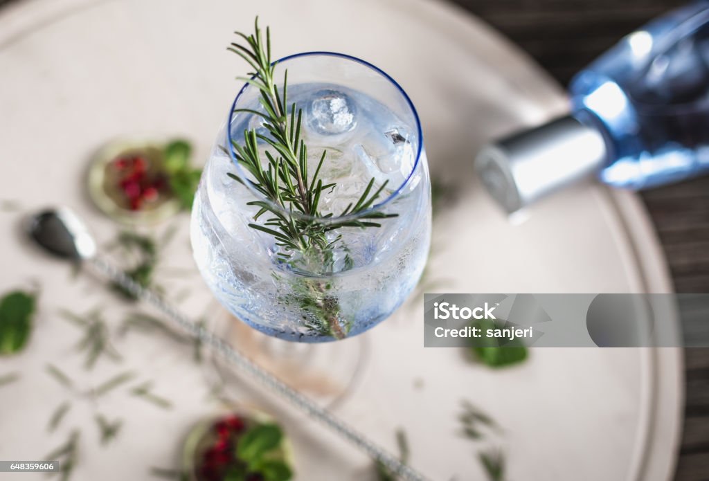Gin Soda with a Rosemary Decorated Gin Soda with a Rosemary Leaf on a wooden desk Gin Stock Photo
