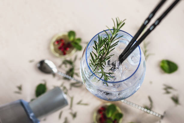 Gin Soda with a Rosemary Decorated Gin Soda with a Rosemary Leaf on a wooden desk tonic water stock pictures, royalty-free photos & images