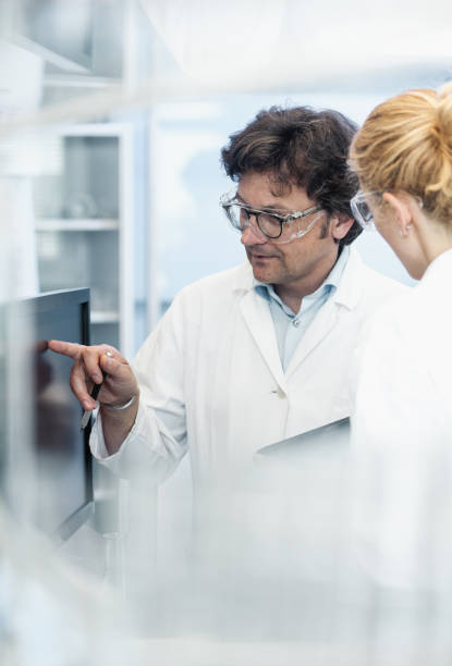 istock Scientists in a Laboratory Standing Beside Computer Monitors and Discussing 648366998