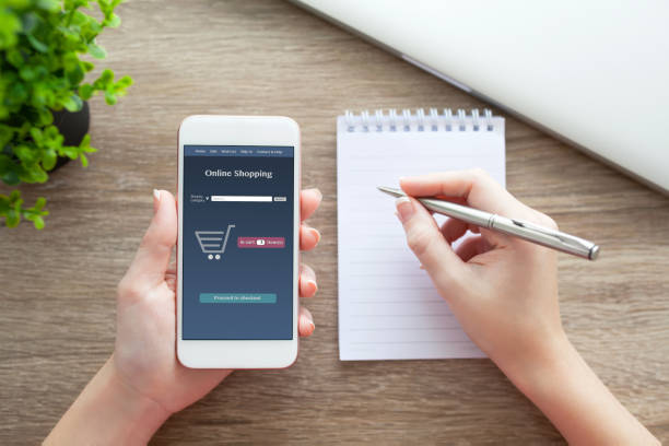 istock female hands holding phone with online shopping and pen notebook 648374530