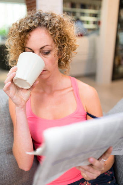istock woman on the sofa reading the newspaper 648381366
