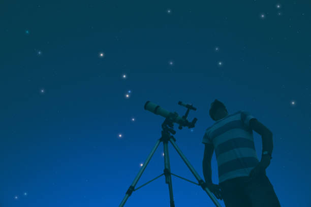 istock Man enjoying under the starry sky with telescope beside him. My astronomy work. 648384672