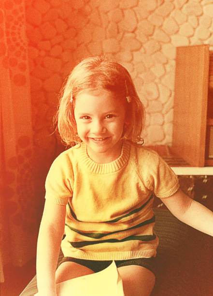 Vintage high key photo of a little girl sitting indoors from the seventies.