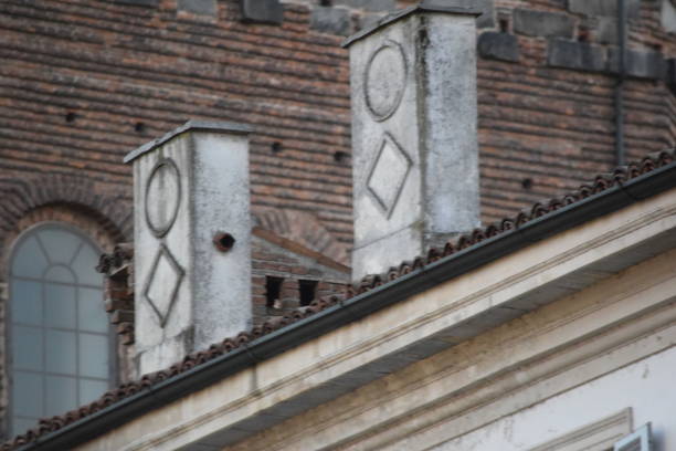 Pavia, Italia -January 5, 2017: two chimneys decorated with a geometrical pattern  in Piazza della Vittoria, Pavia. In the back the wall of The Duomo di Pavia