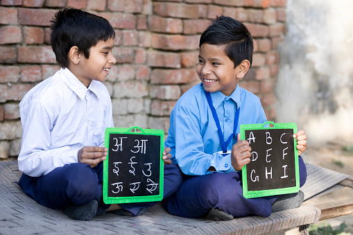 Portrait of school boys in uniform holding slate with alphabet on it