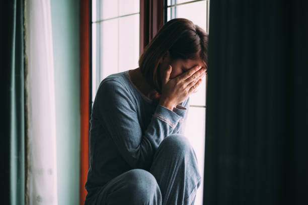 istock Young sad woman sitting on the window 648419162