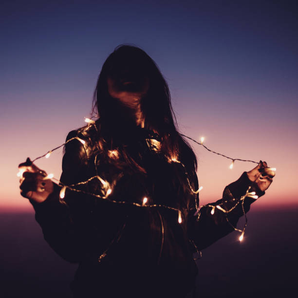 woman with decorate light at top of mountain in colorful twilight