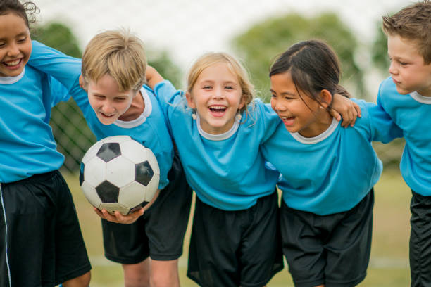 Friends on a Soccer Team A multi-ethnic group of elementary age children are standing together before their soccer game. One girl is smiling and looking at the camera. team sport photos stock pictures, royalty-free photos & images