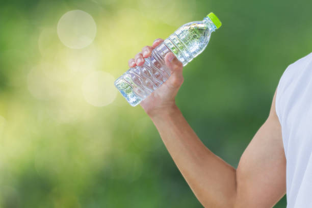 istock Man holding water bottle on blurred green bokeh background 648421074