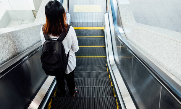 istock asian woman walking down  on the escalator 648424850