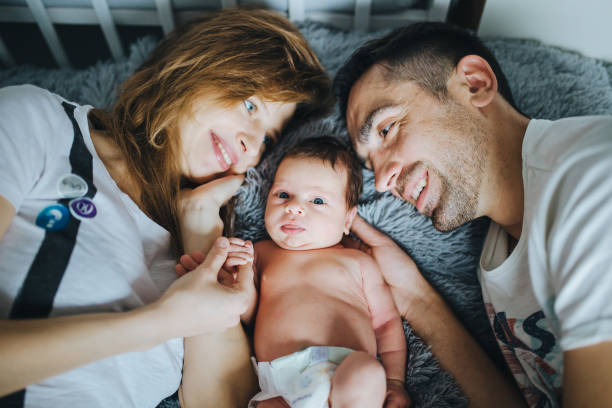 istock Young parents lying in bed with small newborn baby between them 648431046