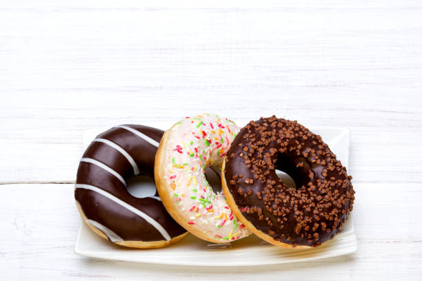 istock Tasty donuts with icing and chocolate on white wooden background 648442076