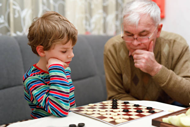 bambino bambino e nonno anziano giocare insieme da dattieri gioco - concentration chess playing playful foto e immagini stock