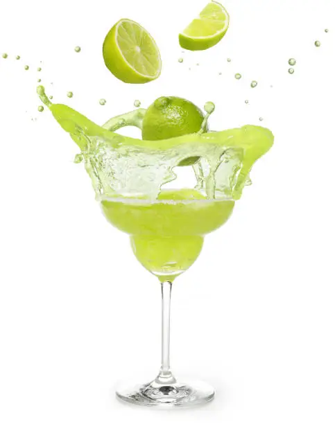 lime falling into a margarita cocktail splashing isolated on white background