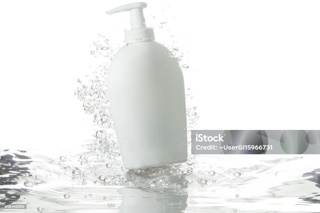 liquid soap dispenser and bubbles over rippled water white soap dispenser and flying bubbles over water surface Splashing Stock Photo