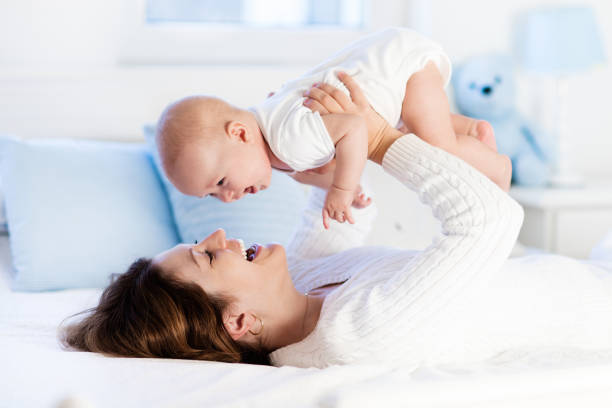 baby and mother at home in bed. mom and child. - mother baby new kissing imagens e fotografias de stock