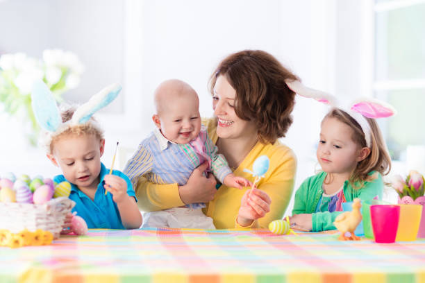 istock Mother with three children painting Easter eggs 648449828