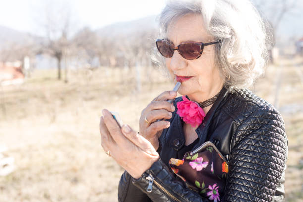 istock Senior woman applying lipstick 648452710
