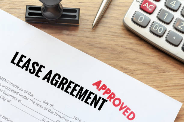 Approved lease agreement document with rubber stamp and calculator on wooden desk. stock photo