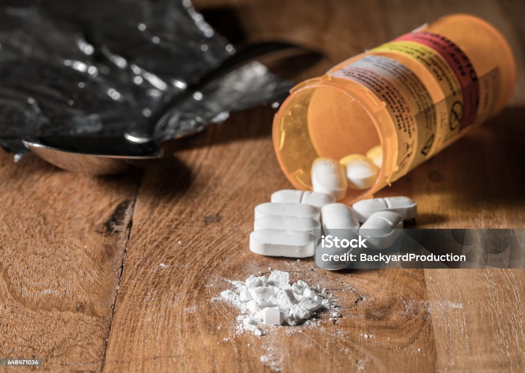 Macro of oxycodone opioid tablets Oxycodone is the generic name for a range of opoid pain killing tablets. Prescription bottle for Oxycodone tablets and pills on wooden table for opioid epidemic illustration Opioid Stock Photo