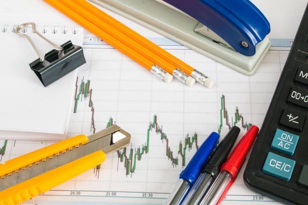 istock Finance chart on a white background with calculator, coins, pens, pencils and paper clips 648484970