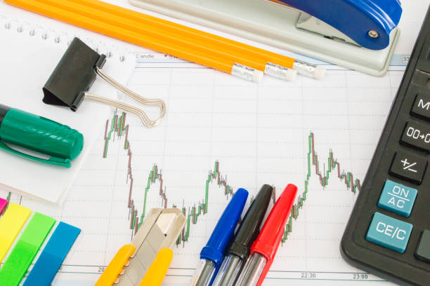 istock Finance chart on a white background with calculator, coins, pens, pencils and paper clips 648485032