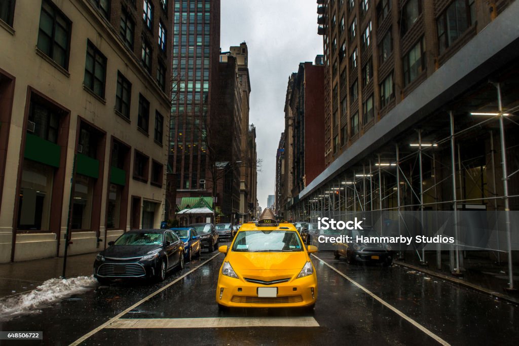 New York City cityscape in rainy day New York City cityscape in rainy day. There are large group of cars on the road. All cars in a row.  Some of them are parked side of the road. Some of them on the road and moving forward.  A yellow taxi in front of all other cars. Focus on a yellow taxi. Horizontal composition. Image taken with Nikon D800 and developed from Raw format. Car Stock Photo