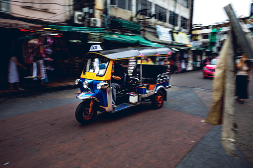 Bangkok, Thailand, December 9, 2022. Traditional tuk tuk taxis and tourists in Ram Buttri street. Street near Chakrabongse road.
